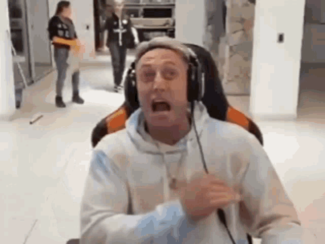 a man wearing headphones and a hat is sitting in a chair .