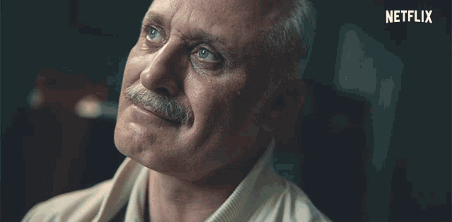 a man with a mustache is smiling with a netflix logo in the background