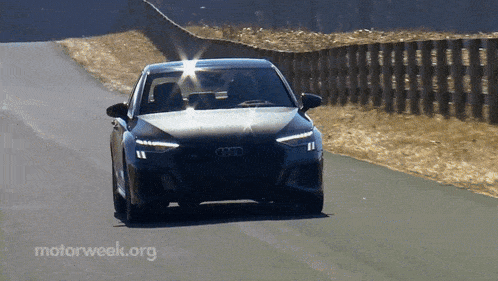 a black audi is driving down a road