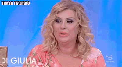 a woman with red nails is sitting in front of a sign that says trash italiano on it