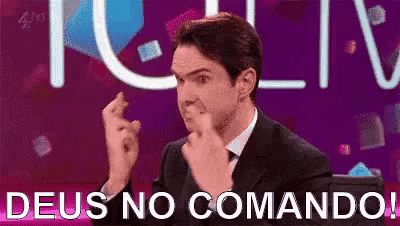 a man in a suit and tie is sitting in front of a sign that says deus no comando