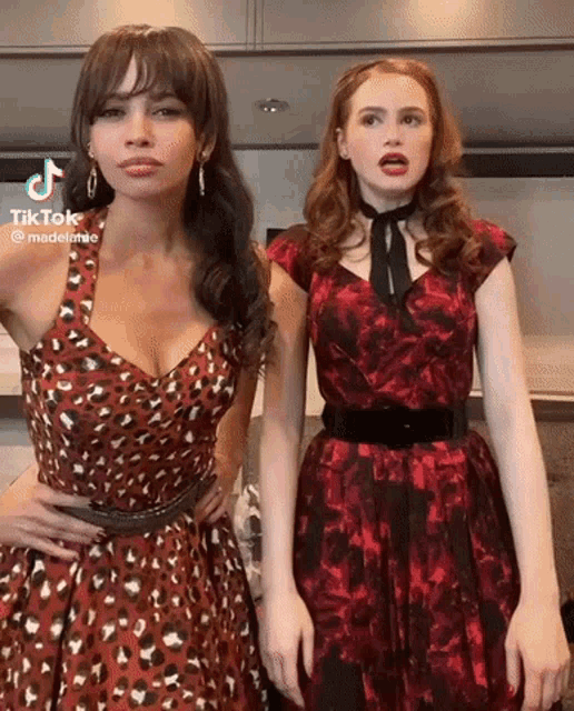 two women in red dresses are standing next to each other and making funny faces .