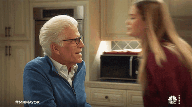 a man in a blue sweater is talking to a woman in a kitchen with the hashtag #mrmayor