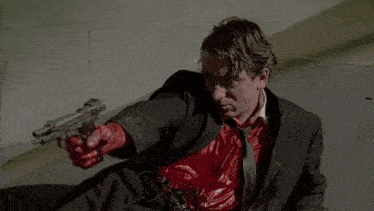 a man in a suit is laying on the floor with blood on his clothes