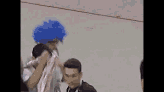 a man wearing a blue wig and a pink shirt is being thrown in the air .