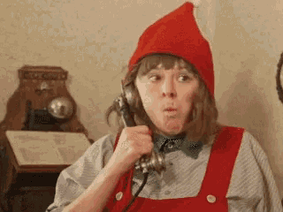 a woman in a red hat is talking on a telephone .