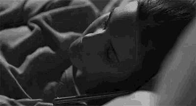 a black and white photo of a woman laying in bed with a gun .