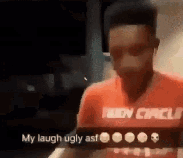 a man in a red shirt is laughing while looking at a tablet .