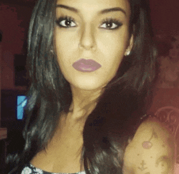 a close up of a woman 's face with a cherry tattoo on her arm