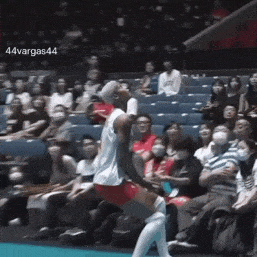 a volleyball player is jumping in the air in front of a crowd of people .