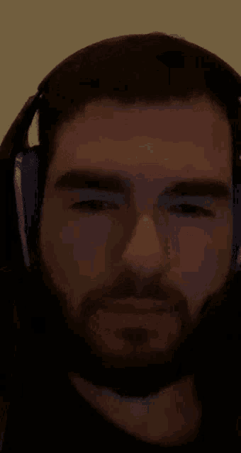 a man with a beard is wearing headphones and looking at the camera