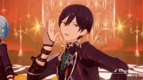 a boy with black hair and blue eyes is giving a peace sign while standing on a stage .