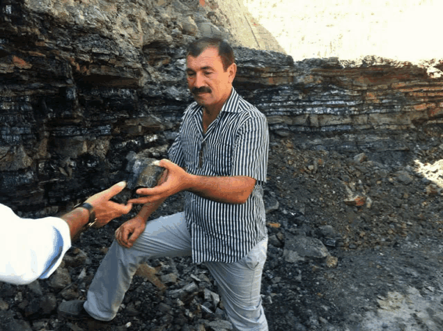 a man in a striped shirt is holding a large rock in his hand