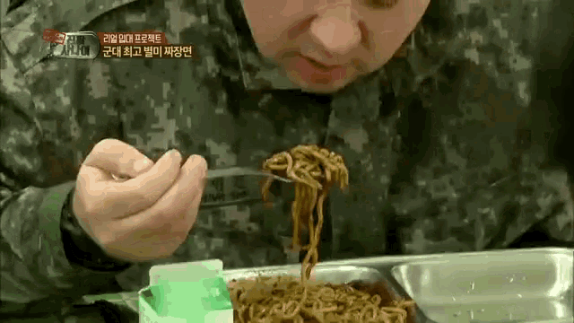 a man in a military uniform eating noodles with a fork