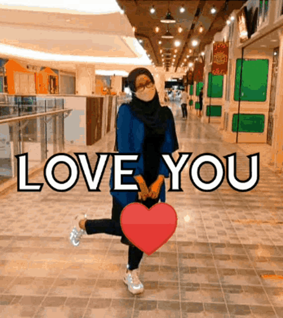a woman wearing a face mask is holding a heart and says i love you .