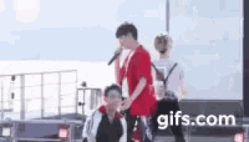 a man in a red shirt is holding a microphone while another man looks on .
