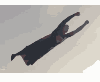 a man dressed as superman is flying through the air .