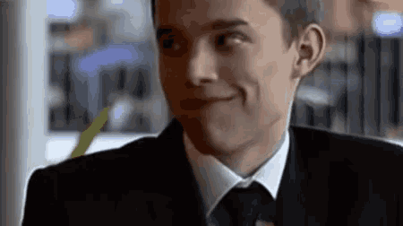 a man in a suit and tie is smiling while sitting at a table in a restaurant .