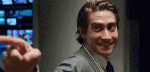 a man in a suit and tie is smiling and pointing at the camera while wearing headphones .