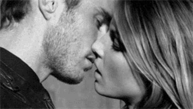 a man and a woman are kissing each other in a black and white photo .