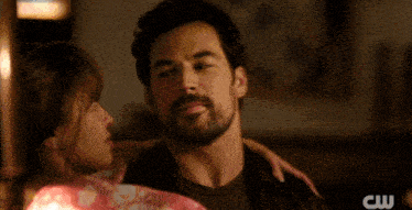 a close up of a man and woman hugging with the cw logo in the corner
