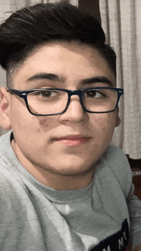 a young man wearing glasses and a shirt that says tommy on it
