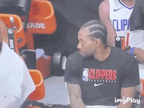 a man wearing a black shirt that says clippers sits in the stands