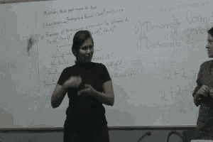 a woman is standing in front of a white board with numbers written on it