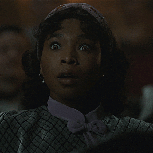 a woman wearing a headband and earrings looks surprised in a dark room