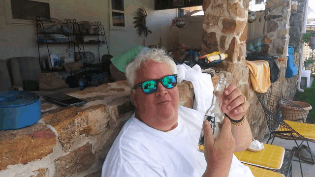 a man wearing sunglasses is holding a bottle in his hand