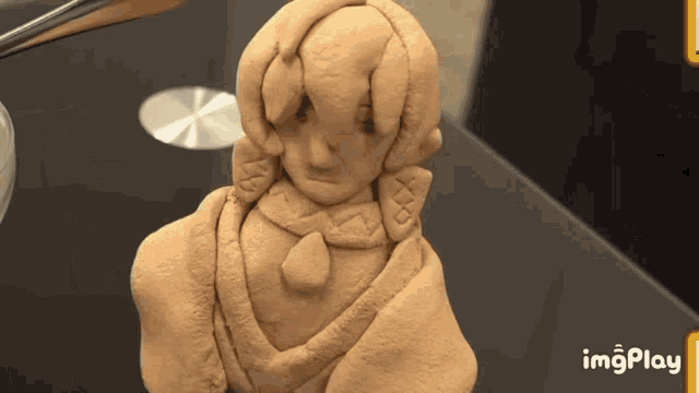 a statue of a girl is on a table next to a imgplay button