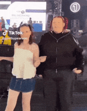 two women are dancing in front of a large screen with the number 1 on it