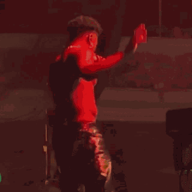 a man in a red shirt and black pants is standing on a stage holding a microphone .