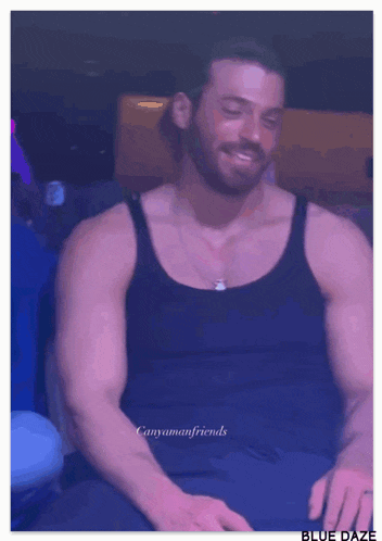 a man with a beard wearing a black tank top and a necklace .