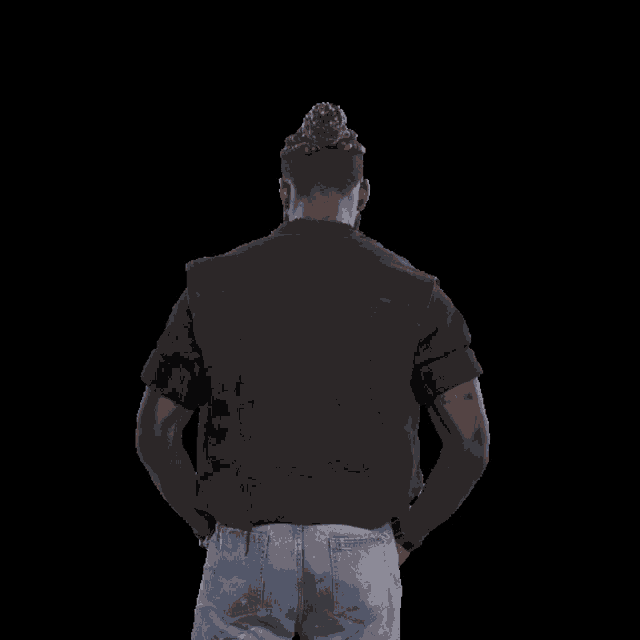 the back of a man wearing a black vest and jeans