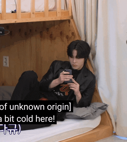 a man laying on a bunk bed looking at his cell phone