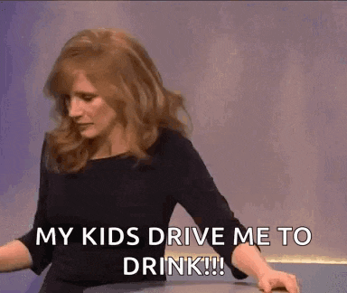 a woman is sitting at a table with her arms crossed and says `` my kids drive me to drink ! ''