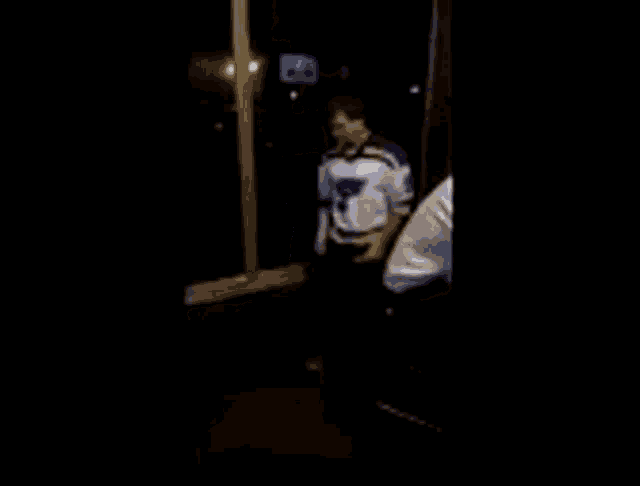 a man in a st louis blues jersey is dancing in a dark room