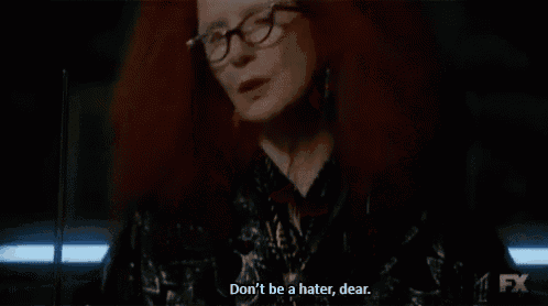 a woman with red hair and glasses is talking to someone .