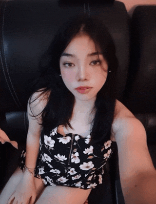 a woman in a black and white floral dress is sitting on a black couch