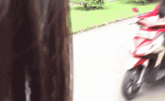 a woman standing next to a red motorcycle on a street .