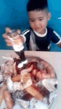 a young boy is standing next to a bowl of shrimp and ice