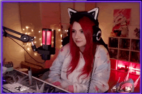 a woman with red hair and cat ears is sitting in front of a microphone in a room .