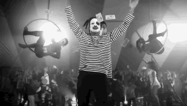 a black and white photo of a man in a clown costume holding money