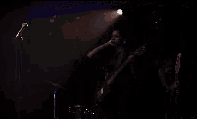 a woman singing into a microphone while a man plays guitar