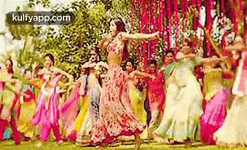 a woman is dancing in front of a crowd of people in a field .