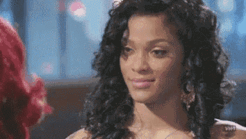 a woman with curly hair is smiling and looking at another woman with red hair .