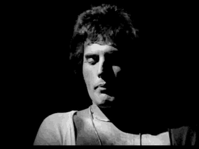 a black and white photo of a man with his eyes closed in a dark room .