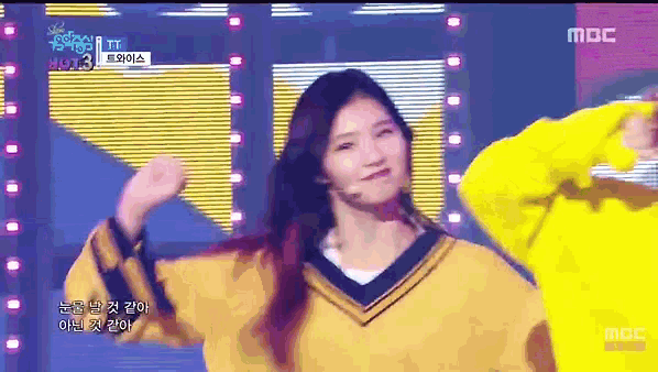 a girl in a yellow sweater is dancing on a stage in front of a mbc logo