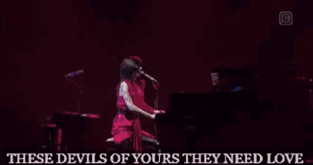 a woman singing into a microphone while playing a piano
